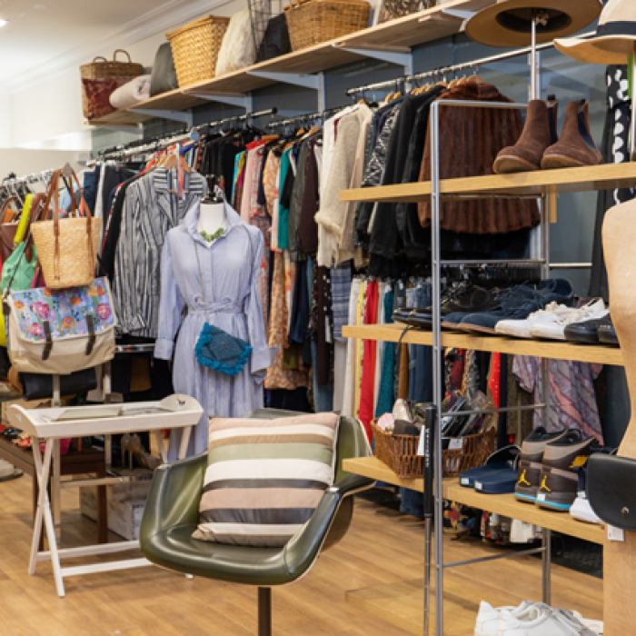 Interior of a boutique-style thrift store with racks of clothes, accessories, and a mannequin on display.