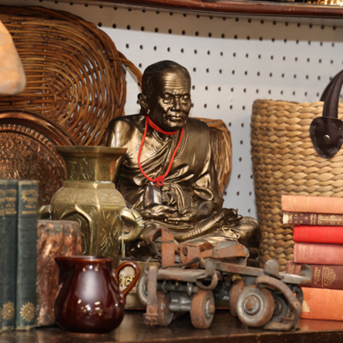 Assortment of vintage items including books, a brass statue, woven basket, and decorative objects on a shelf.