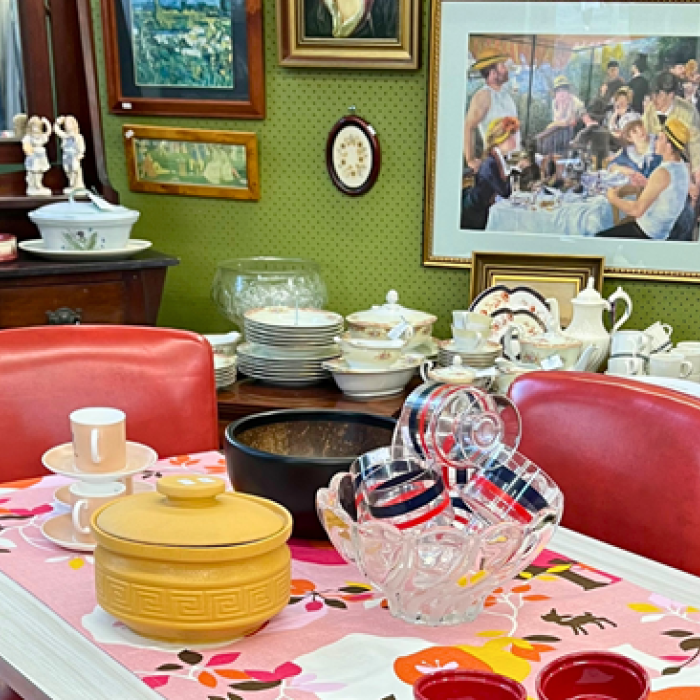 Vintage dining setup with red chairs, colorful tableware, and framed art on a green wall.