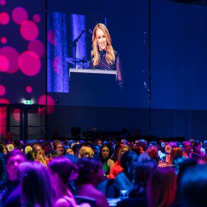 crowd at event with woman speaking on podium