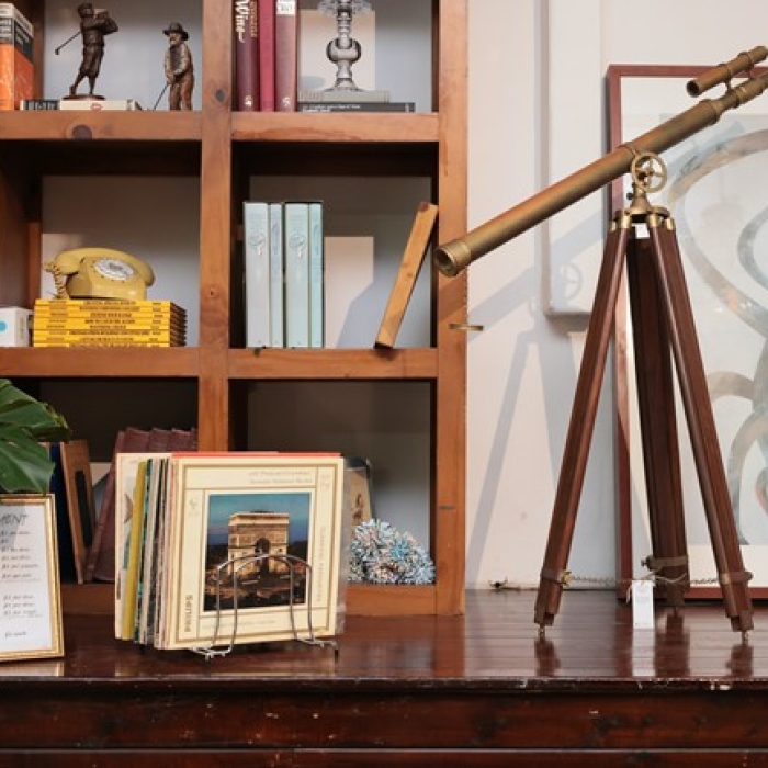 Vintage telescope, books, and decor items displayed on a wooden shelf and table.
