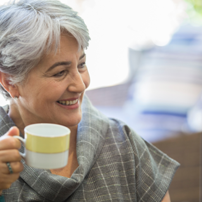 woman smiling and holding a coffee cup