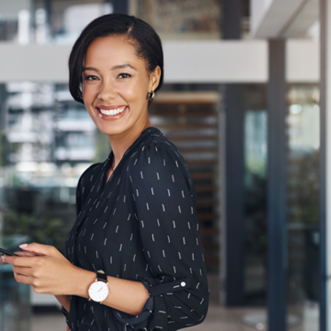 Smiling woman holding a phone in an office.