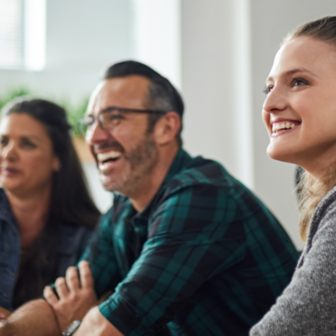 Three people smiling and listening during a meeting.